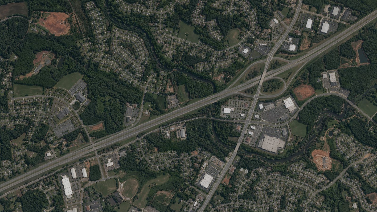 Aerial view of a southern town with neighborhoods, highways and tree cover.